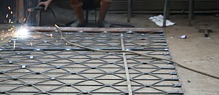 A picture with a man working on a metall structure